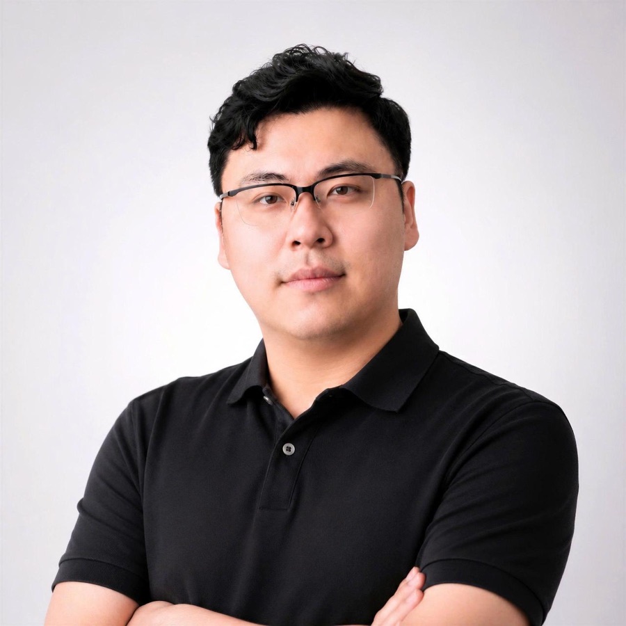 Michael La in a black polo and rimless glasses, arms crossed
